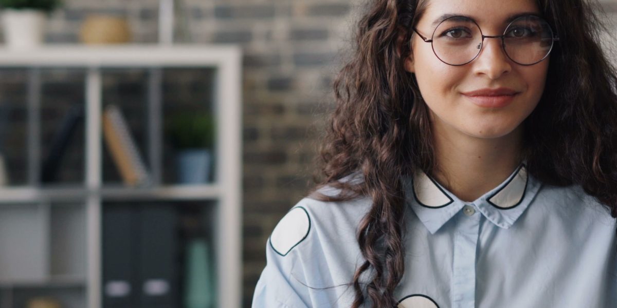 A professional looking confident and smiling in an office environment, representing successful career progression.