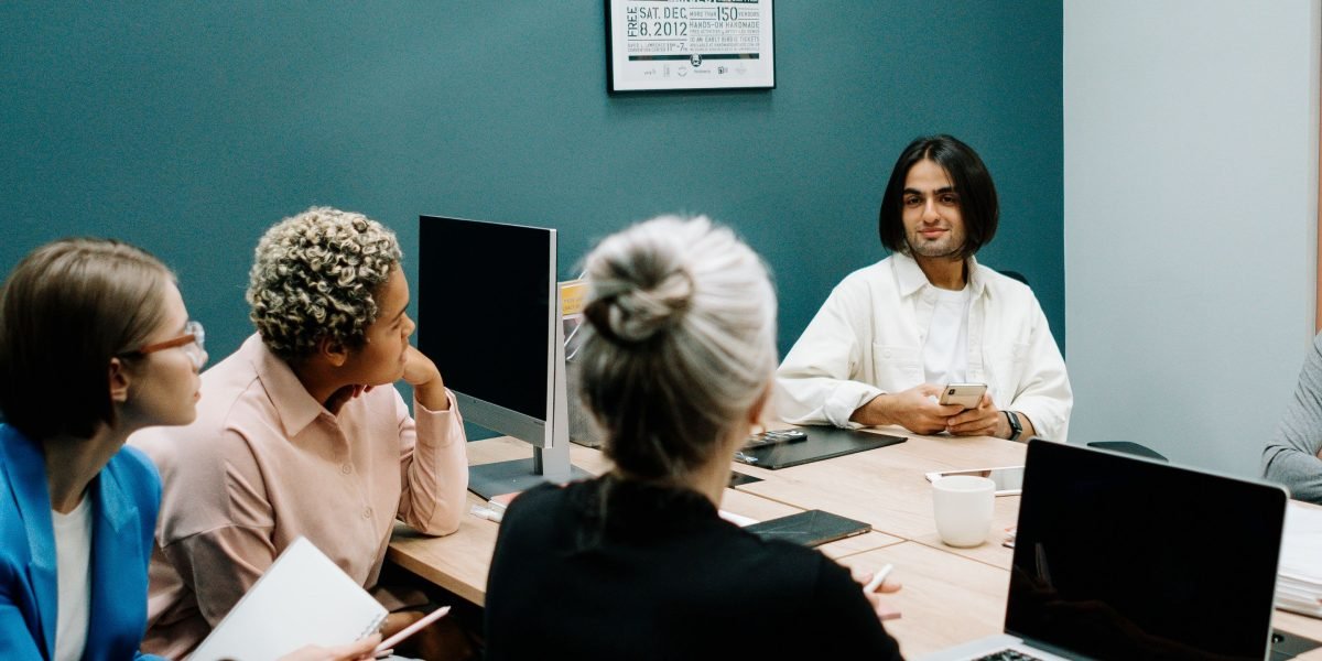 A group of professionals in a modern office setting discussing complex topics, representing ML engineers, product leads, and investors engaging with new AI technologies.